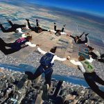 Skydivers forming a circle in freefall over a city and farmland