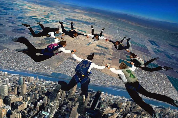 shutterstock_1587051190 Skydivers forming a circle in freefall over a city and farmland