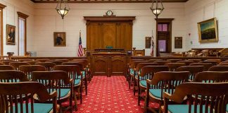A $16 Million Scam Just Ended In Prison Courtroom with wooden benches facing the judge's bench