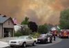Emergency vehicles respond to wildfire near suburban homes