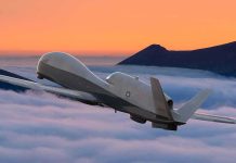 military drone flying above clouds at sunset