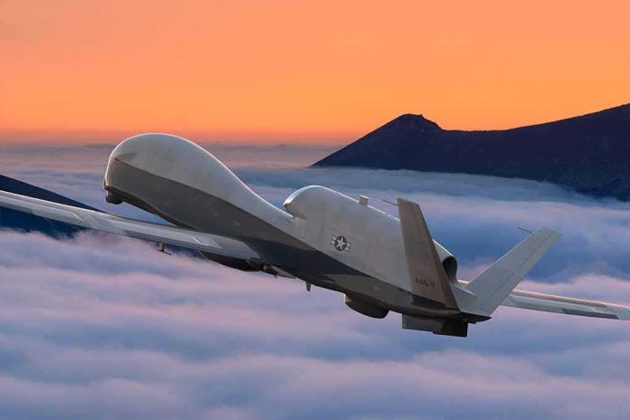 military drone flying above clouds at sunset
