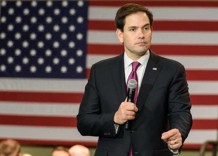 shutterstock_375031759 Marco Rubio speaking with a microphone in front of a large American flag