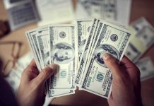 Hands counting US hundred-dollar bills