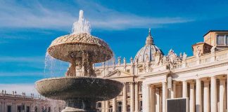 Stone fountain in front of a grand basilica with dome and colonnade