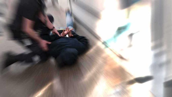 shutterstock_1098127790 person being restrained on the ground in a hallway