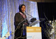 Ilhan Omar speaking at a podium on a decorated stage