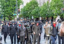 On-Camera Meltdown: AG Denies His Own Words group of masked protesters walking through a city street