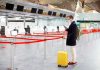 One Item in CIA Recovery Kit Raises Eyebrows Traveler wearing a mask stands by yellow suitcase at empty airport check-in