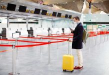 One Item in CIA Recovery Kit Raises Eyebrows Traveler wearing a mask stands by yellow suitcase at empty airport check-in