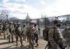Carlos Hyde, Tavon Wilson, Dontrelle Inman, Brian Folkerts, Brock Coyle, Curtis Lofton, and Chuck Howley among soldiers walking past fencing near the U.S. Capitol