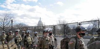 Carlos Hyde, Tavon Wilson, Dontrelle Inman, Brian Folkerts, Brock Coyle, Curtis Lofton, and Chuck Howley among soldiers walking past fencing near the U.S. Capitol