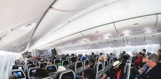 Airplane cabin with passengers seated in economy class