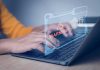 Hands typing on laptop with digital warning alert overlay