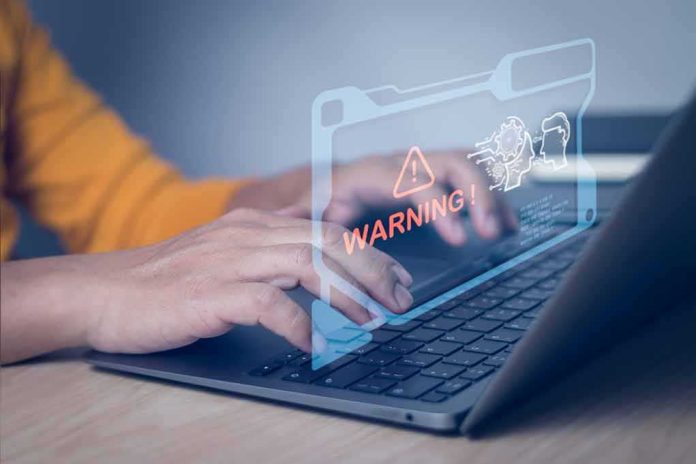 Hands typing on laptop with digital warning alert overlay