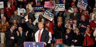 Boxing Legend Shocks Trump Rally Donald Trump addresses a rally crowd at a podium, raising his fist