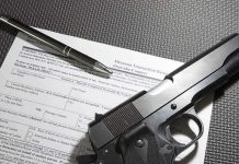 Handgun on firearm transaction form with pen