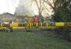 Capital Murder Shock: Sons Found, Gun Nearby Yellow police tape marking a restricted area at a fire scene with firefighters in the background