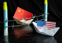 China and USA flags in paper boats with barbed wire