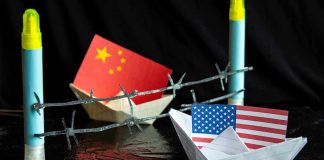 China and USA flags in paper boats with barbed wire