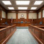 Empty courthouse courtroom with wooden benches and chairs.
