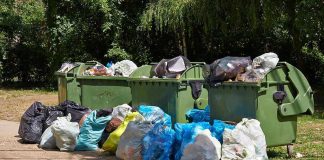 Overflowing garbage bins with bags on the ground