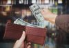 A hand withdrawing cash from a wallet in a blurred background