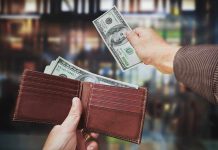 A hand withdrawing cash from a wallet in a blurred background