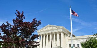Supreme Court building with American flag and surrounding greenery