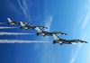 Four military jets flying in formation against a blue sky leaving smoke trails
