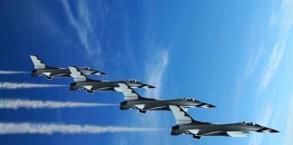 Four military jets flying in formation against a blue sky leaving smoke trails