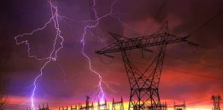 Lightning strikes illuminate a power station against a colorful sunset sky