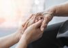 Young hands holding an elderly persons hand.