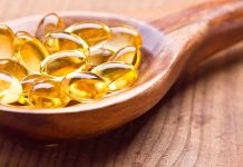 Golden omega 3 capsules in a wooden spoon