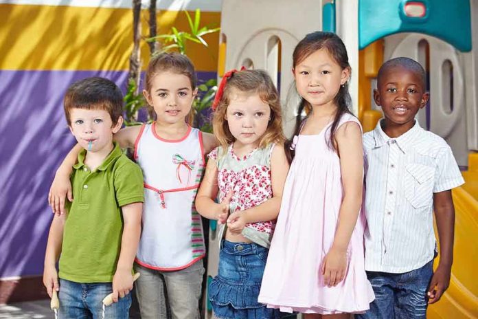 shutterstock_193504529.jpg Five children standing together in a playground setting smiling at the camera